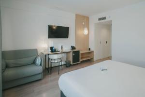 a hotel room with a bed and a couch and a desk at Sercotel Carlos III in Cartagena