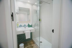 a bathroom with a sink and a glass shower at Sercotel Carlos III in Cartagena +32 photos