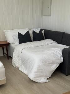 a bed with white sheets and pillows on a couch at Sokkelleilighet på Sola in Sola
