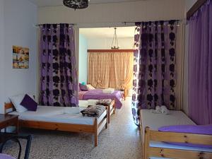 a room with three beds and purple curtains at Eri Studios in Agia Marina Aegina