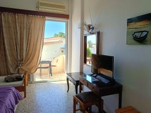 a bedroom with a desk with a television and a window at Eri Studios in Agia Marina Aegina