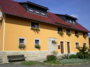 a yellow building with a red roof and a bench at Ferienhof Leuner Sandro in Bad Schandau