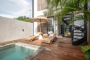 a pool with two chairs and an umbrella on a deck at Modern 2BR Villa Samudra Ocean View Nusa Dua in Ungasan