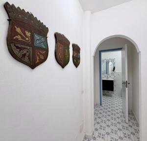 a hallway with three masks on the wall at La Casa al Mare Vulcano in Vulcano