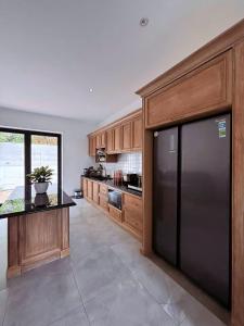 a kitchen with a black refrigerator and wooden cabinets at Camly Resort DaLat in Ấp Ða Lợi