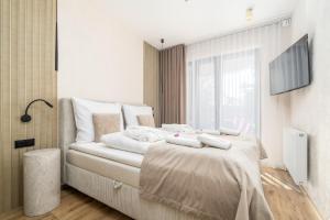 a bedroom with a bed with white sheets and a window at Your Holidays Forest D141 in Międzyzdroje