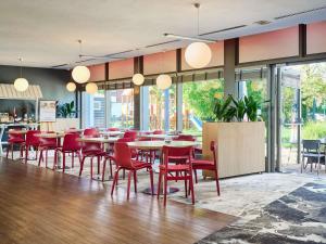 a restaurant with red chairs and tables and windows at Novotel Wrocław City in Wrocław