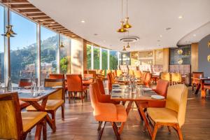 a restaurant with wooden tables and chairs and large windows at Sterling Kodai Valley in Kodaikānāl