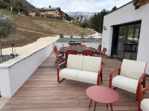 a patio with chairs and a table on a deck at L'Orée du Peney in Saint-Jean-dʼArvey
