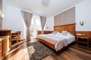 a bedroom with a bed and a table and a desk at Wellness Hotel Kager Harkány in Harkány