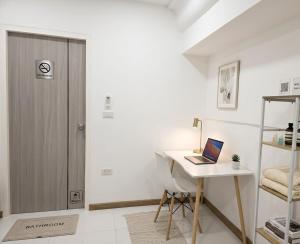 a white room with a desk with a laptop on it at Huggdaily 6 in Ban Khlong Thewa