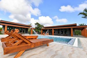 a pool with a wooden bench in front of a house at Kenting Four Season Villa in Hengchun South Gate