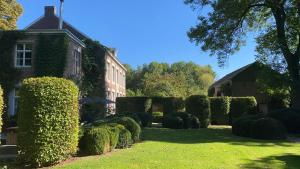 a garden with trimmed hedges in front of a building at Roomer in Landen +1 photo