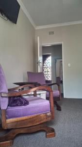 a living room with purple chairs and a table at Melody Guest House in Centurion