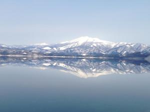 a snow covered mountain is reflected in the water at Lodge Yodel in Senboku