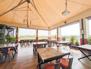 a restaurant with tables and chairs and large windows at Hotel Solaris in Indore