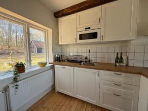a kitchen with white cabinets and a sink and a window at Fiskarhuset - seaside cottage 4 pax in Sjöbo