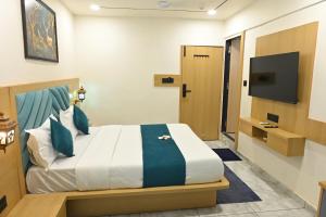 a hotel room with a bed and a tv at Hotel Revanta Inn in Ahmedabad