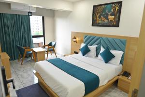 a hotel room with a bed and a table and chairs at Hotel Revanta Inn in Ahmedabad +27 photos