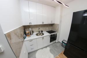 a kitchen with white cabinets and a sink and a refrigerator at Apartman Imperial 7 in Sarajevo