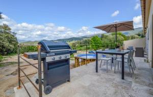 a grill and a table with an umbrella on a patio at "Vigna d’Eugène" – T3 Piscine | by Efficios in Petreto-Bicchisano