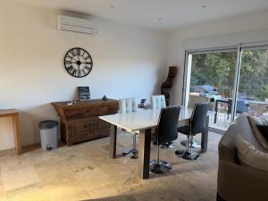 a living room with a table and chairs and a clock at "Vigna d’Eugène" – T3 Piscine | by Efficios in Petreto-Bicchisano