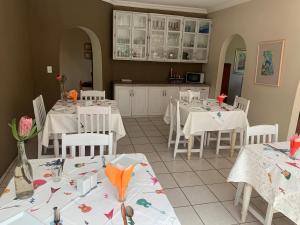 a dining room with white tables and white chairs at Melody Guest House in Centurion