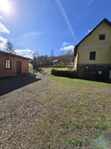 a house on a gravel road next to a building at Pod modříny in Adršpach +9 photos