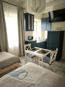 a bedroom with a table and a kitchen with blue cabinets at Studio Apartment Self Check-in in Mažeikiai