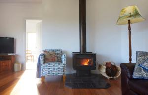 a living room with a fireplace and a couch and chair at Mereweather Estate Cottage in Dunkeld