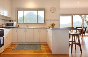 a kitchen with white cabinets and a large window at Mereweather Estate Cottage in Dunkeld