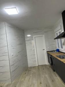 a kitchen with white marble walls and a white door at El rincón del pintor in Villacañas