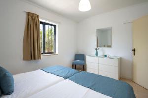 a bedroom with a bed and a chair and a window at Mouraliz Apartments by HD PROPERTIES - Vilamoura Marina in Vilamoura