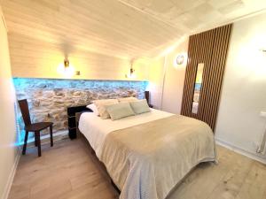 a bedroom with a bed and a stone fireplace at L'Horizon - Maison en Pierres, Vue Alpes et Nature in La Burbanche