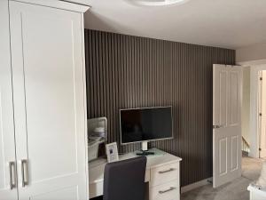 a room with a desk with a computer and a television at Quiet double bedroom in Yapton