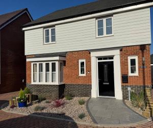 a brick house with a black door and a driveway at Quiet double bedroom in Yapton