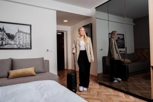 a woman standing in a bedroom with a suitcase at Urban Boutique Hotel Center in Ljubljana