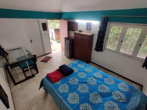 a bedroom with a blue bed with a red pillow on it at New Creation Guest House in Auroville