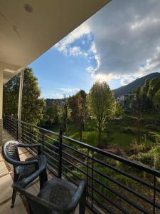 a balcony with two chairs and a view of a field at Soma House Dharamkot in McLeod Ganj