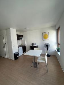 a living room with a white table and a kitchen at Apparteo Strasbourg in Strasbourg