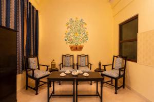 a dining room with chairs and a table and a painting on the wall at Kalyan Villa Heritage Stay in Udaipur