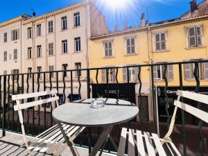 a table and chairs on a balcony with buildings at Suite Notre Dame - Appartements in Cannes
