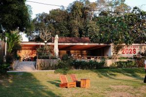 a house with two wooden chairs in the yard at Vả Riverside Retreat in Hue