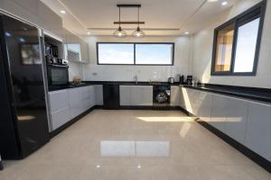 a large kitchen with white cabinets and a black refrigerator at Villa Bonheur - Piscine sans vis-à-vis in Berkane