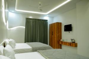 a hotel room with two beds and a television at Arthanaa Villa in Mysore