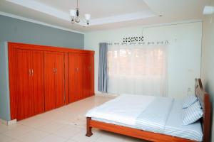 a bedroom with a bed and wooden cabinets and a window at Inkindi House in Kigali