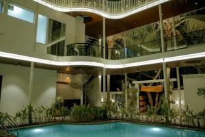 a large building with a swimming pool and plants at Arthanaa Villa in Mysore