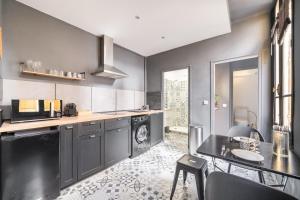a kitchen with gray cabinets and a table and chairs at L’Escapade Nîmoise - grand studio centre Nîmes in Nîmes