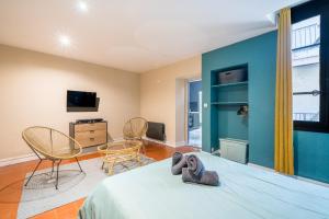 a room with a bed and chairs and a tv at L’Escapade Nîmoise - grand studio centre Nîmes in Nîmes