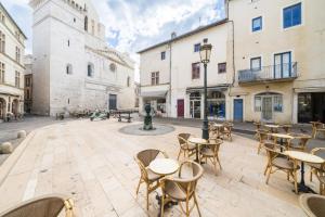 a courtyard with tables and chairs and buildings at L’Escapade Nîmoise - grand studio centre Nîmes in Nîmes